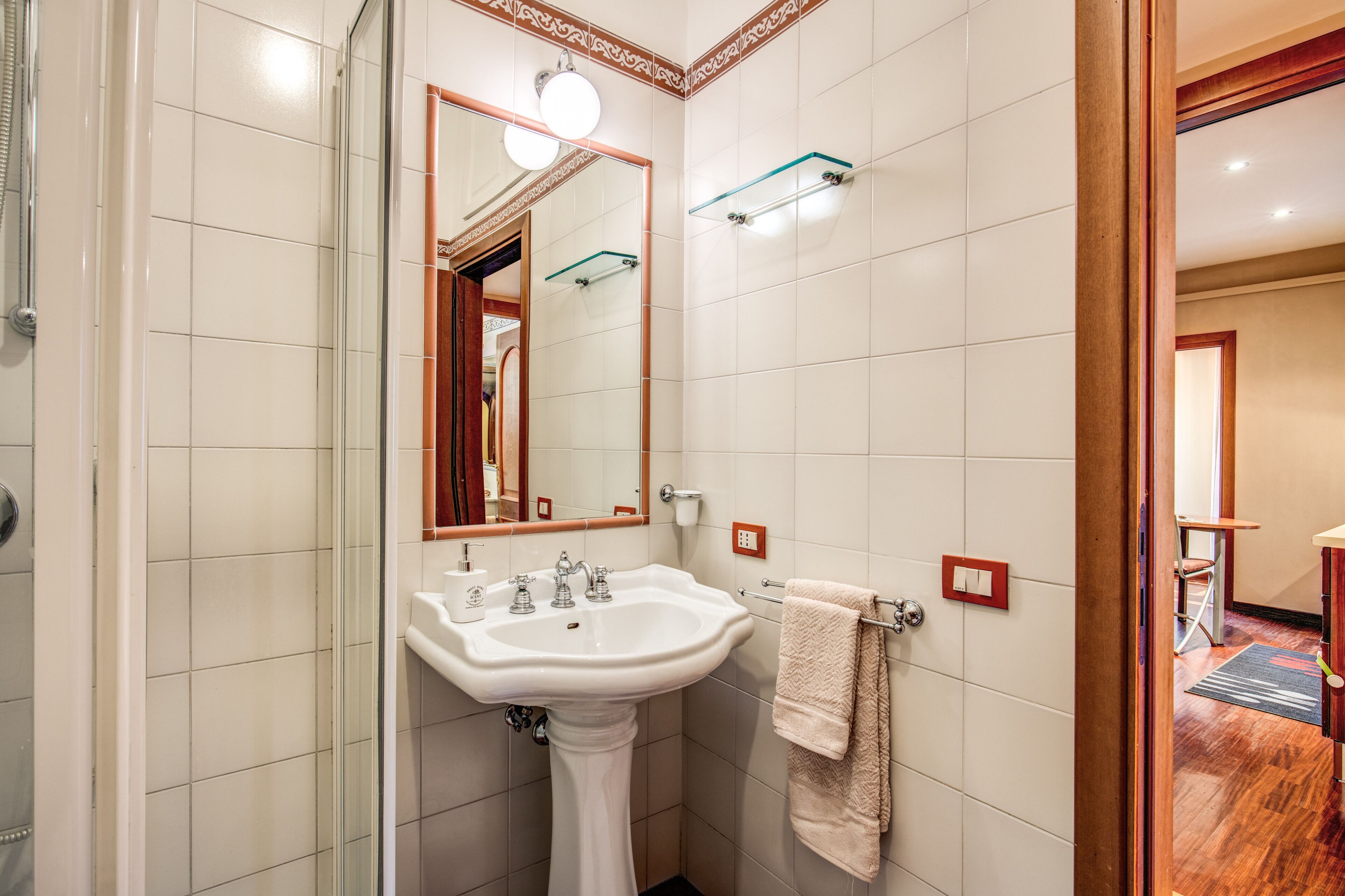 A bathroom with a white sink, mirror, and glass shower enclosure.