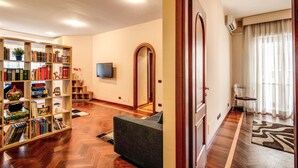 A living room with a bookshelf, a sofa, a television, and a wooden floor. - Beautiful apartment near San Pietro. Comfortable, silent, WI-FI, accessories. (Roma)