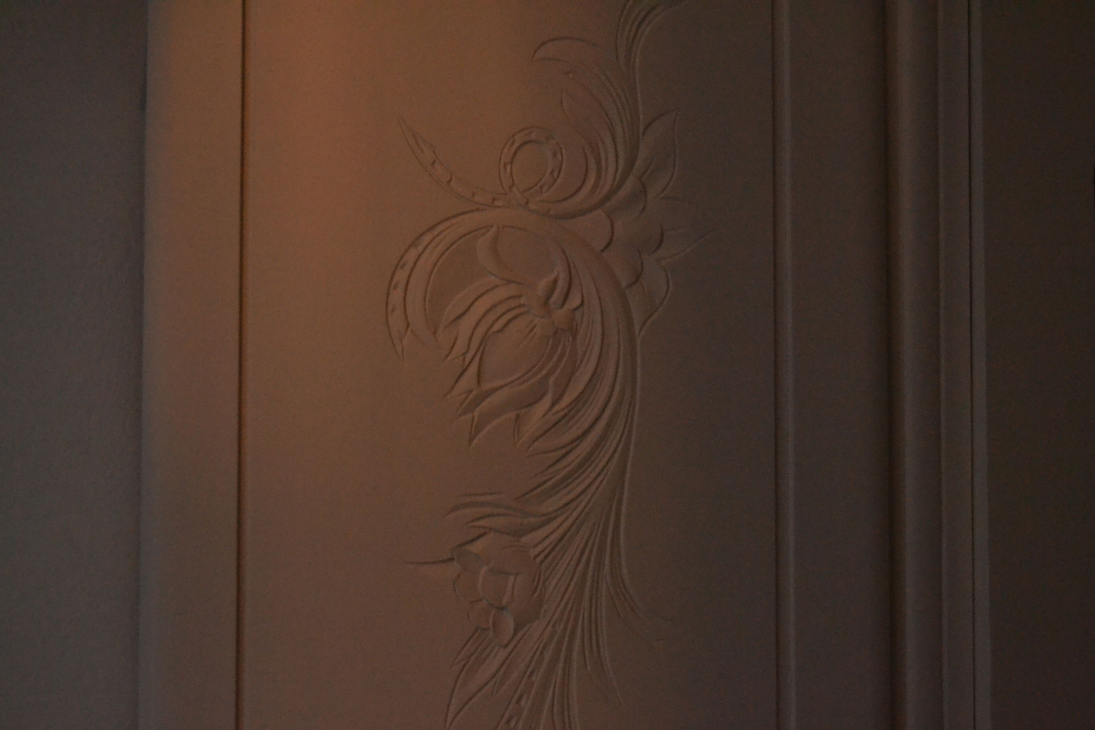 Un mur orné d’un décor en relief représentant des motifs floraux.