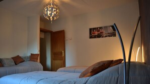 Ein Schlafzimmer mit zwei Betten, einem Chandelier, einer Tür und einem Wandbild.