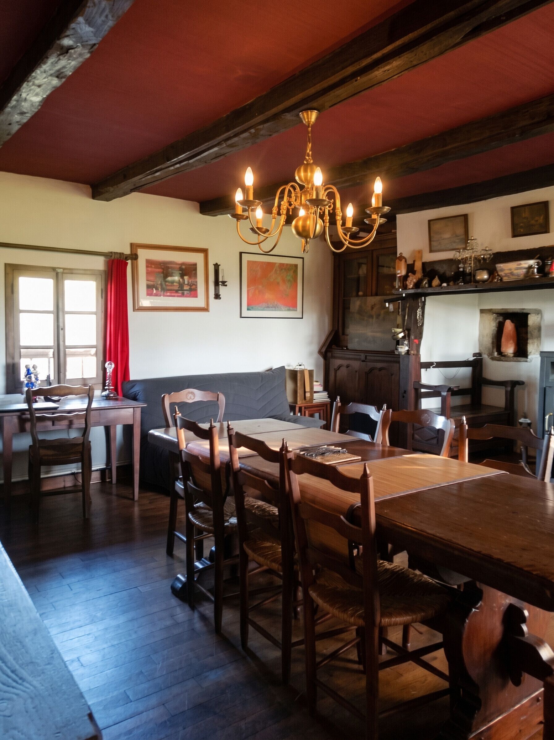 A dining area with a wooden table and chairs, a chandelier, and a kitchen area with a stove and shelves.