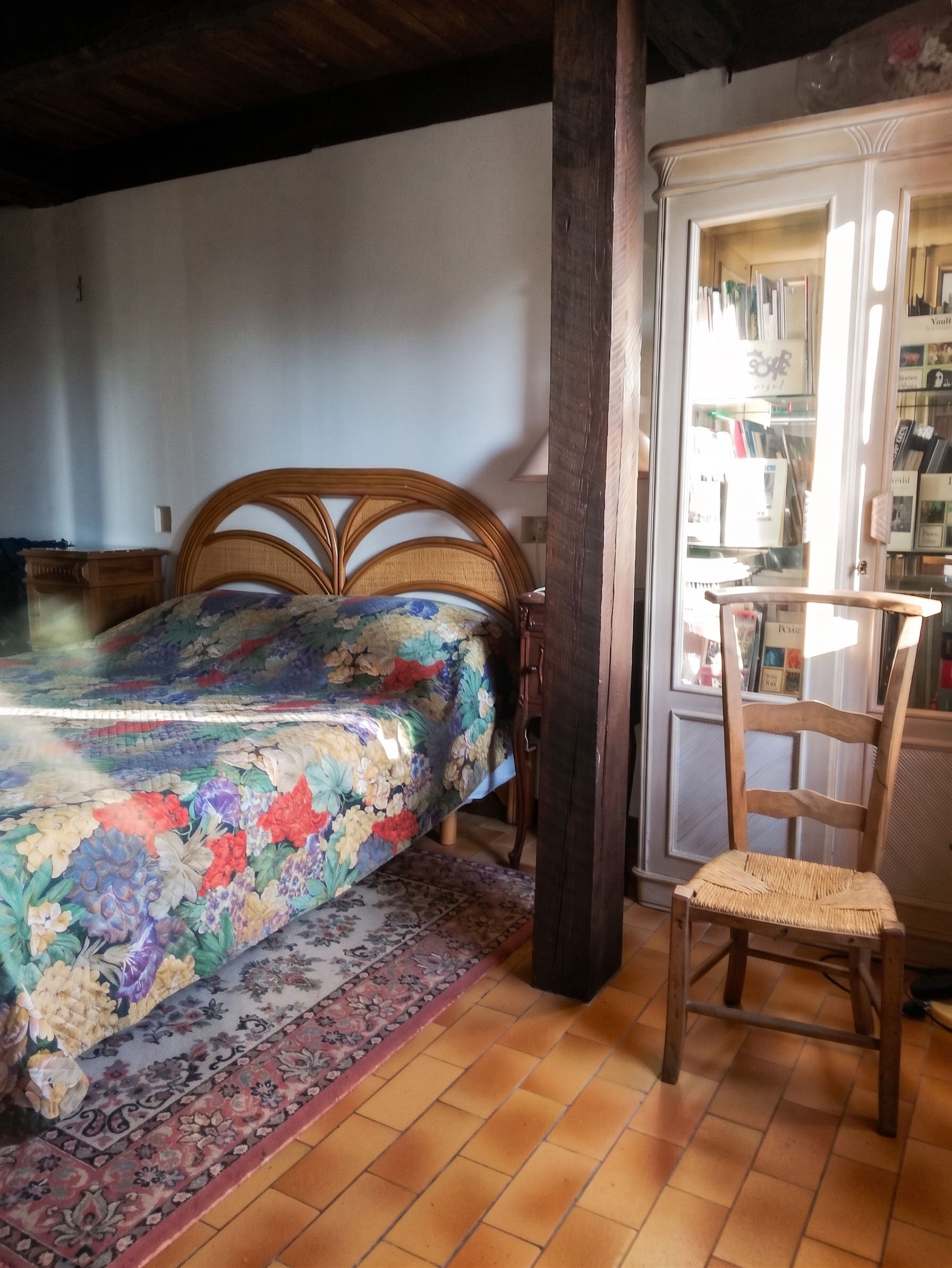 Ein Schlafzimmer mit einem Bett, einem Sessel, einem Bücherregal und einer Tür zu einem anderen Raum.