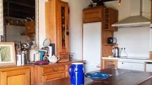 A kitchen with wooden cabinets, a large island, and a hanging light fixture.
