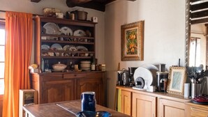A kitchen with wooden beams, a central island, and a shelf with dishes.