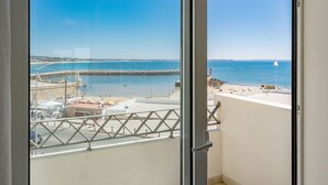 Een balkon met uitzicht op een strand en een helderblauwe lucht.