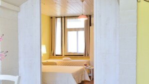 A room with a bed, a small table, a lamp, and a window with curtains.