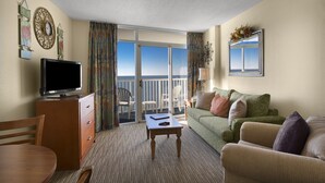 A hotel room with a television, a dining table, a sofa, and a balcony with a view. - Gorgeous Direct Oceanfront King Suite + Official On-Site Rental Privileges (Myrtle Beach)