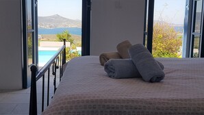 Et soveværelse med seng, to håndklæder og udsigt til en pool og bjerge.
