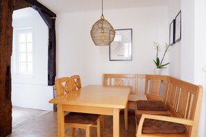 A dining area with a wooden table and bench, a hanging light fixture, and framed artwork on the wall. - Privatzimmer in bester Altstadtlage (Tuebingen)