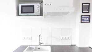 A modern kitchen with white cabinetry, a built-in microwave, and a stainless steel sink. - Privatzimmer in bester Altstadtlage (Tuebingen)