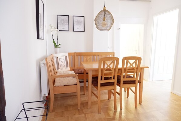 A dining area with a wooden table and chairs, a hanging light fixture, and framed pictures on the wall. - Privatzimmer in bester Altstadtlage (Tuebingen)