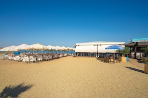 A beachside restaurant with outdoor seating, umbrellas, and a view of the sea. - Apartamento Acqua (Mar de Pulpi) (San Juan de los terreros)