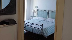 A bedroom with a bed, a nightstand, a lamp, and a mirror. - Garda resort Village in Peschiera el Garda, 
NR CIR 023059-LOC-01384 (PESCHIERA DEL GARDA)