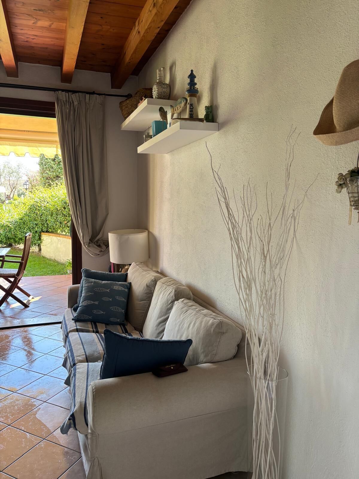 Uma sala de estar aconchegante com um sofá, uma luminária e objetos decorativos nas prateleiras.