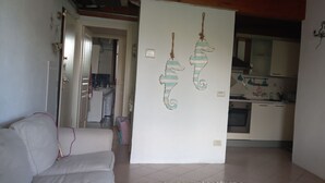 Ein Wohnzimmer mit einer Couch, einer weißen Trennwand und einer Küche im Hintergrund.