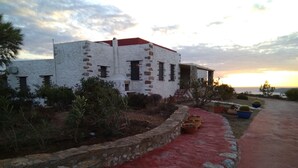 Een wit gebouw met een rood dak, omgeven door een rode looppad en stenen muren.