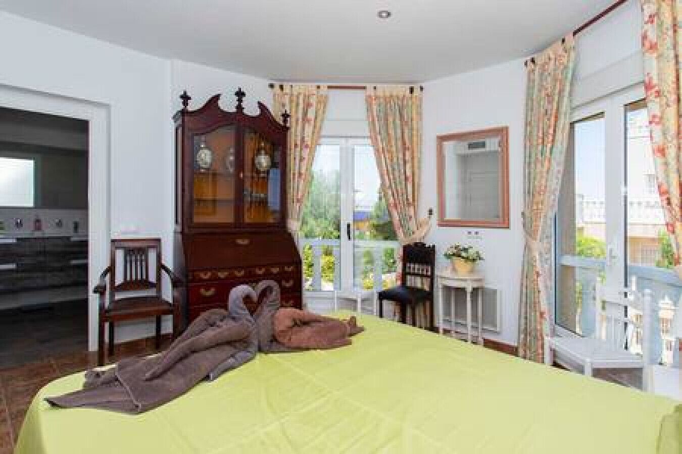 A bedroom with a bed, a wooden cabinet, a chair, and a window with curtains.