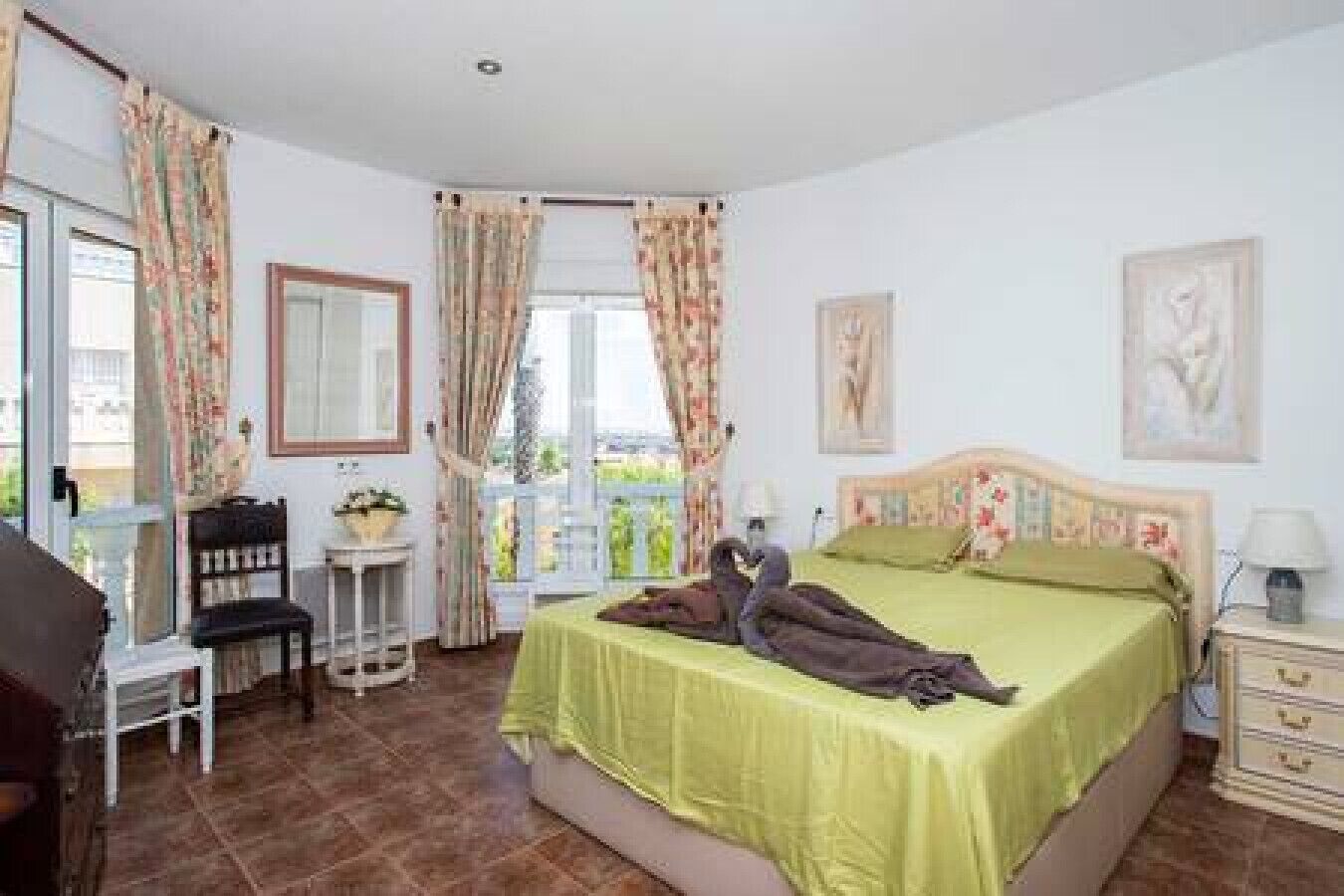 Quarto com cama, escrivaninha, cadeira e janela com cortinas.