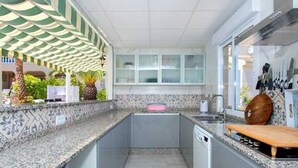 Eine kleine Küche mit einer Arbeitsplatte aus Granit, einem eingebauten Geschirrspüler und einem Holzschneidebrett.