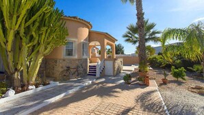 Una casa con fachada de piedra, una bicicleta y una palmera en el jardín.