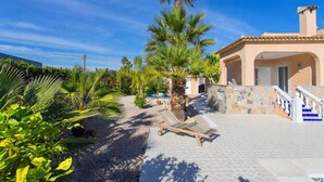 Una villa con patio de tejas, palmeras y zona de piscina.