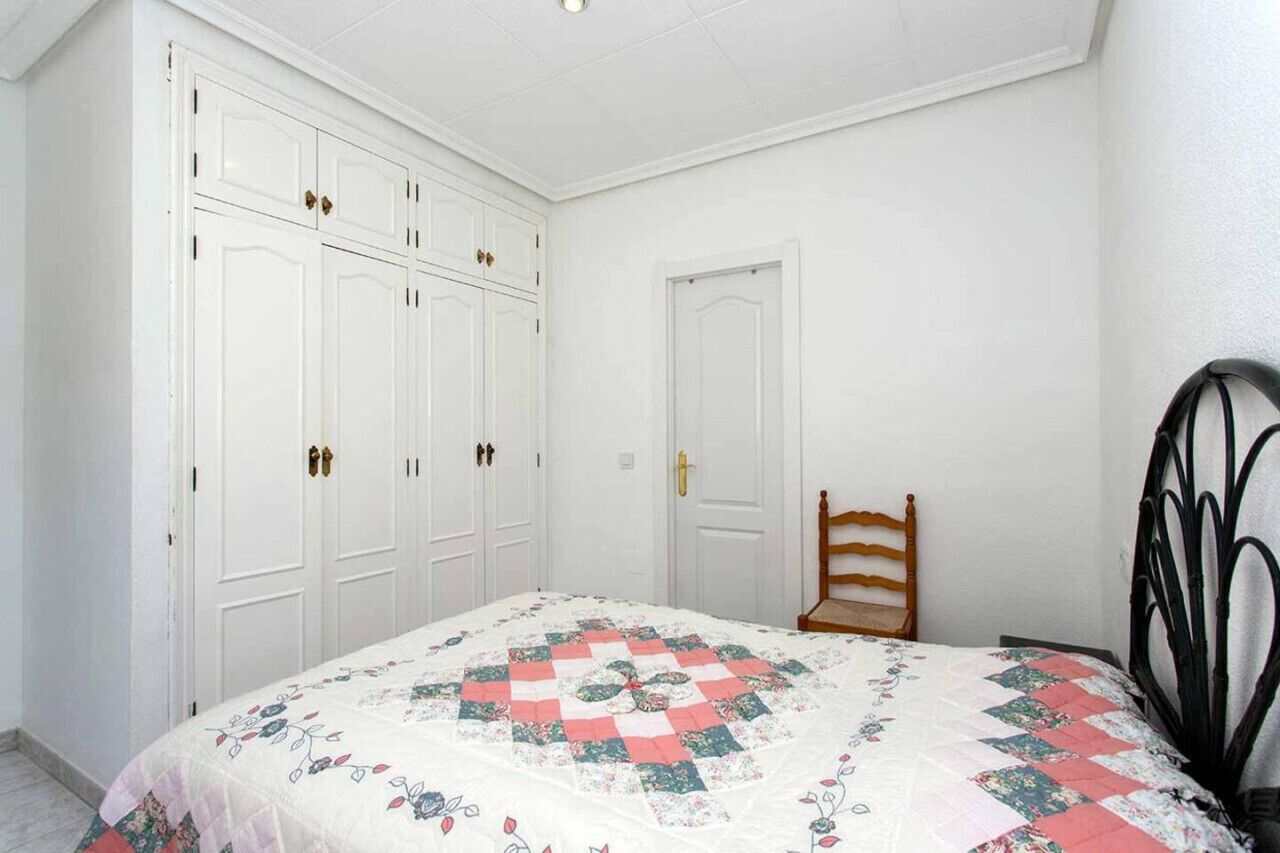 A bedroom with a bed, a wardrobe, and a chair.