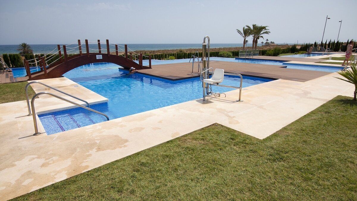 A swimming pool with a bridge, a lifeguard stand, and a view of the ocean.