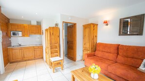 Un espace de vie compact doté de meubles en bois, d’un canapé, d’une table à manger et d’un petit coin cuisine.