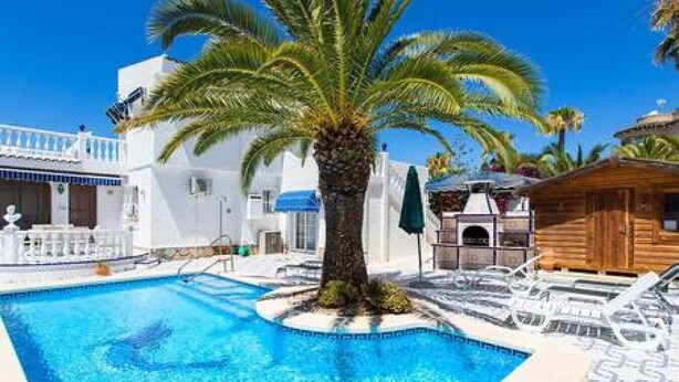 A pool area with a palm tree, a wooden cabin, and a white building with balconies. - CH Villa Sola Ciudad Quesada (Ciudad Quesada)
