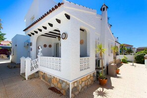 A white building with a stone base, a balcony with a white railing, and potted plants. - CH Villa Sola Ciudad Quesada (Ciudad Quesada)