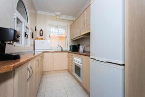 A compact kitchen with a refrigerator, oven, and a microwave. - CH Villa Sola Ciudad Quesada (Ciudad Quesada)