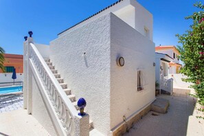 A white building with a staircase leading to a balcony, a pool, and a garden area. - CH Villa Sola Ciudad Quesada (Ciudad Quesada)