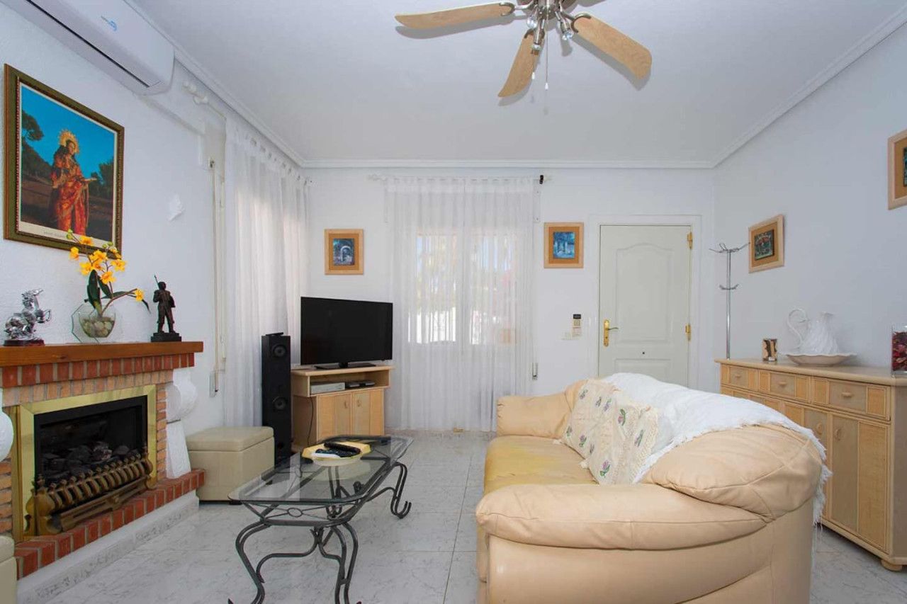 Un salon comprenant un canapé, un téléviseur, une cheminée et un ventilateur de plafond.