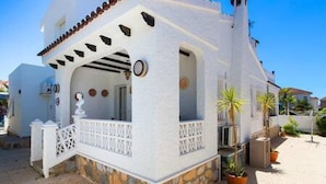 A white building with a stone base, a balcony with white railings, and a door with a circular window. - CH Villa Sola Ciudad Quesada (Ciudad Quesada)