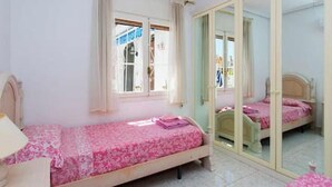 A bedroom with a single bed, a mirror, and a window with curtains. - CH Villa Sola Ciudad Quesada (Ciudad Quesada)