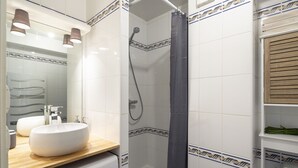 Ein Badezimmer mit einem weißen Waschbecken, einer Holzausziehtheke und einer Dusche mit dunklem Vorhang.