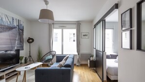 Ein modernes Wohnzimmer mit einer Couch, einem Fernseher und einem großen Fenster.