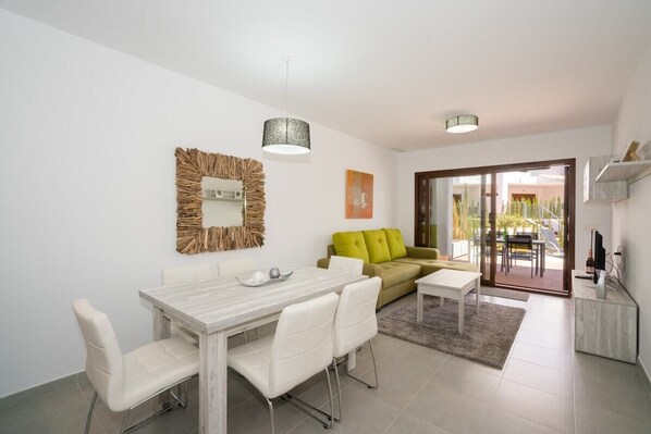 A modern living room with a dining area, a sofa, and a TV. - Apartamento Cerezas (Mar de Pulpi) (San Juan de los terreros)