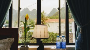 Une pièce avec vue sur les montagnes, une plante en pot, une lampe et deux bouteilles d’eau posées sur un plateau.