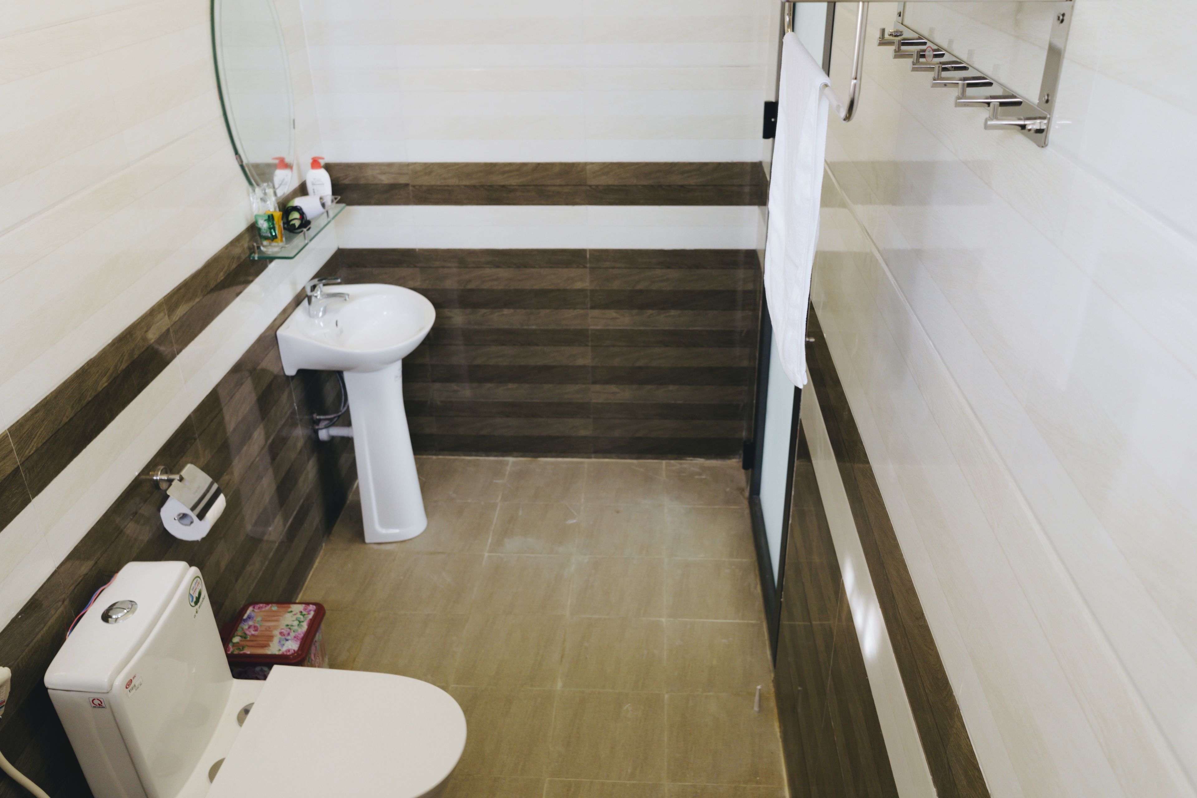 A compact bathroom with a toilet, bidet, and a small shelf with toiletries.
