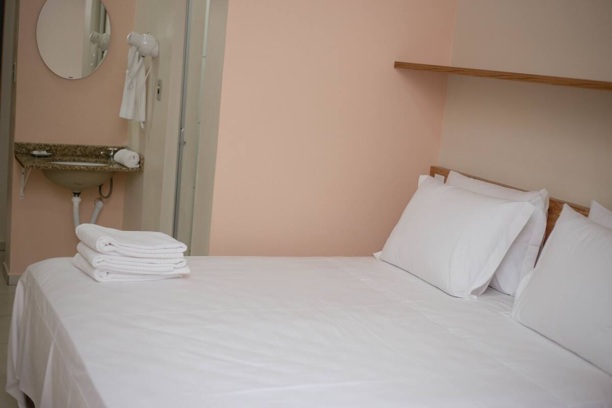Ein Hotelzimmer mit Bett, Waschbecken, Spiegel und Handtuchhalter.