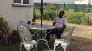 A patio with a table and two chairs, a large umbrella, and a fence in the background. - Hill Rise Retreat One (Harrow Park)