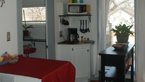 Uma cozinha compacta com micro-ondas, cafeteira e um pequeno espaço de refeições com mesa e cadeiras.