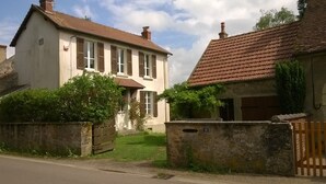 Ein zweistöckiges Haus mit einem Ziegeldach, einem Vorgarten und einem Holztor.