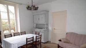 Ein Essbereich mit Tisch und Stühlen, einer hölzernen Bank, einer Couch und einem weißen Schrank mit Fenster darüber.