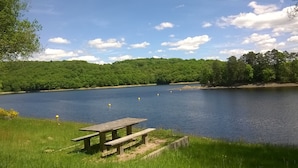 Ein Picknickplatz am Seeufer mit einer Holzbank und einem Picknicktisch.