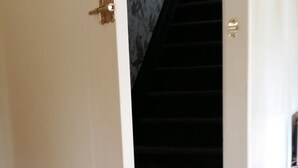 Eine halbgeöffnete weiße Tür führt zu einer Treppe mit dunklem Teppich.