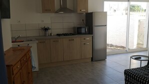 Moderni keittiö, jossa on puukalusteet, mikroaaltouuni, liesi ja jääkaappi.