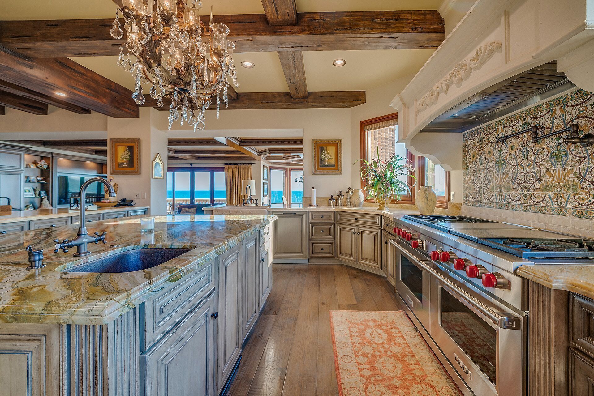 A spacious kitchen with a large island, a double oven, and a chandelier.
