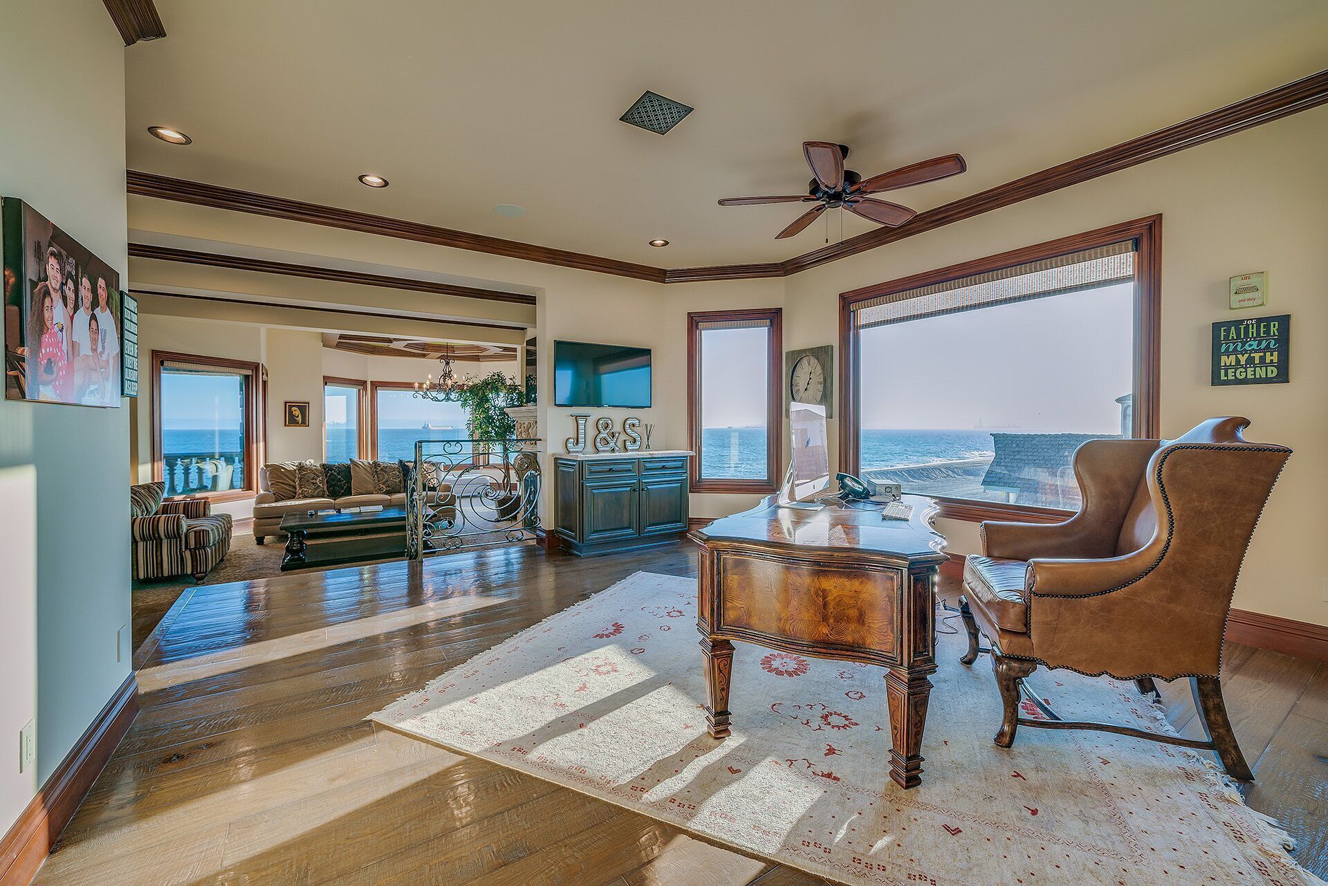 A spacious living room with a view of the ocean, a ceiling fan, and a large window.